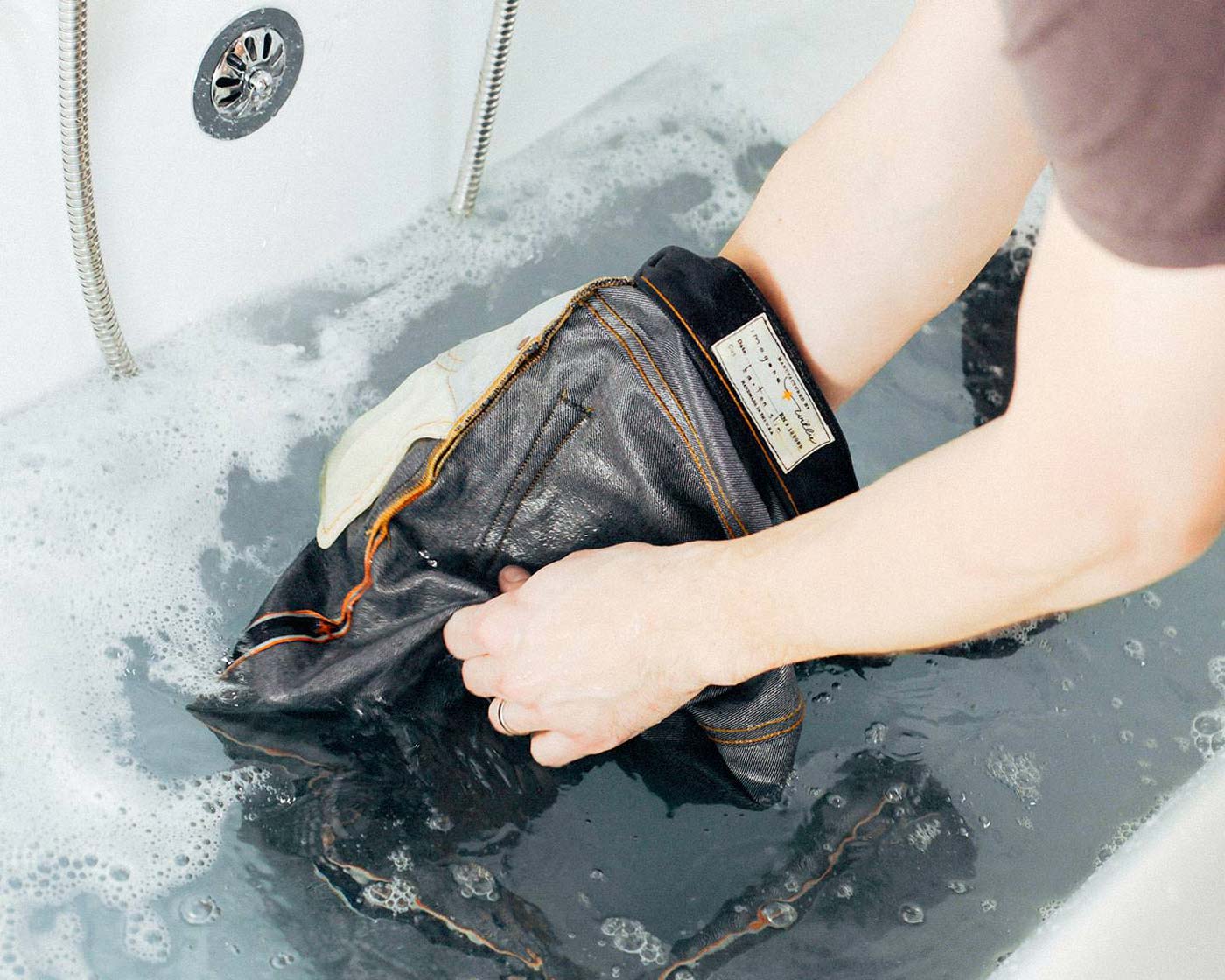a person washing clothes in a bathtub